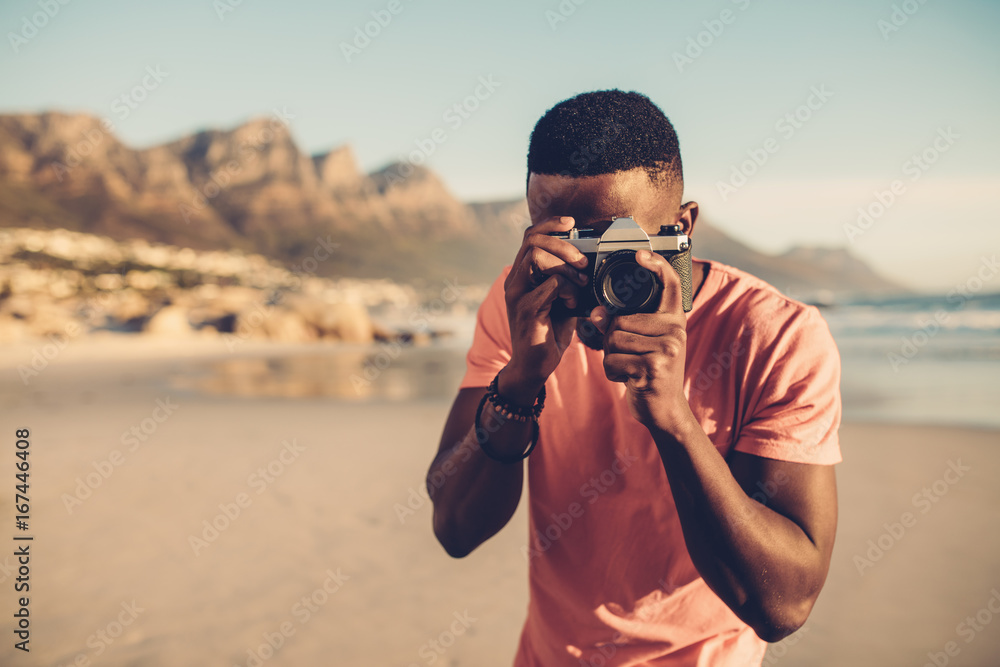 Black guy using digital camera on beach Black guy using digital camera on beach