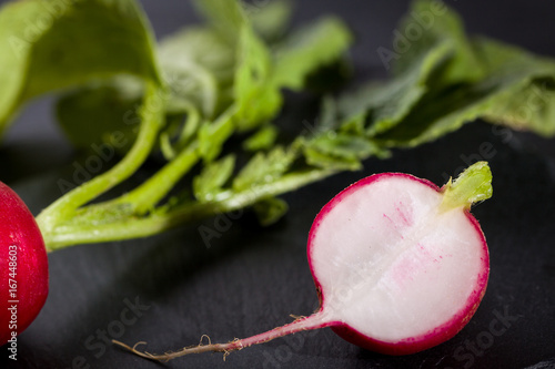 Profile of fresh radish lay on black slate plate.