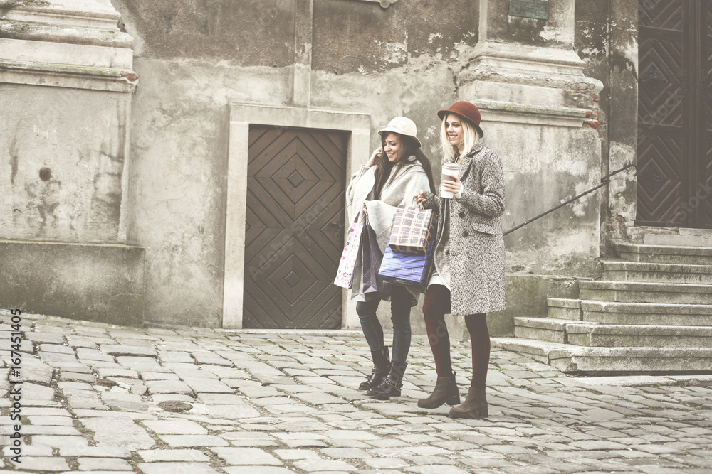 Fototapeta premium Two best friends walking on the street . Young female best friends doing shopping on the streets.