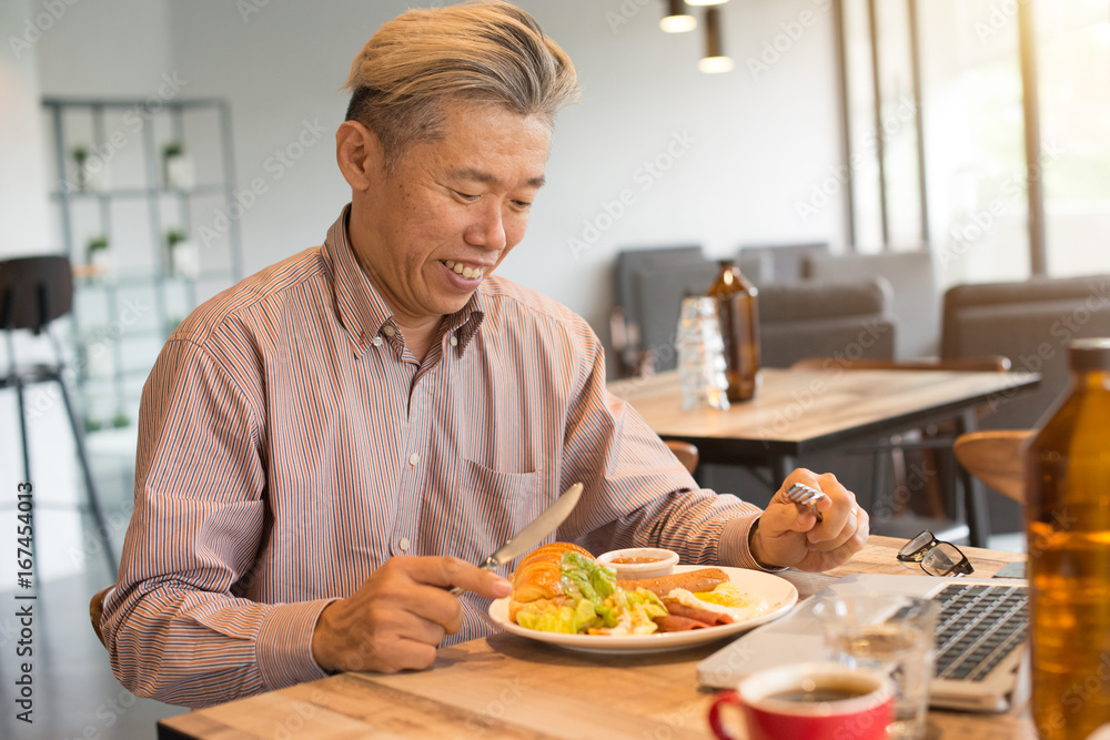 matured asian business male having breakfast
