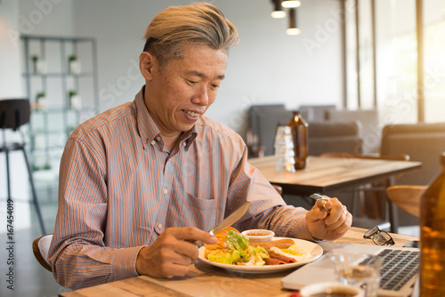 matured asian business male having breakfast
