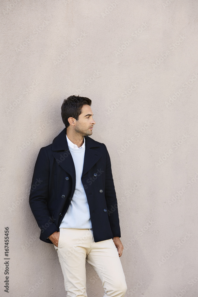 Handsome guy wearing jacket against wall, looking away Handsome guy wearing jacket against wall, looking away