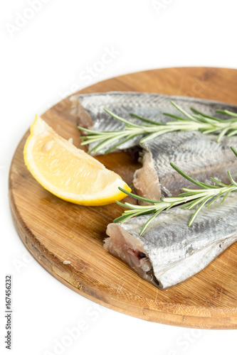 Raw hake fish with lemon and rosemary branches on the wooden board