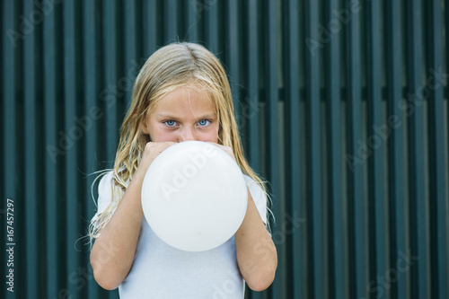 Girl blowing balloon outside photo