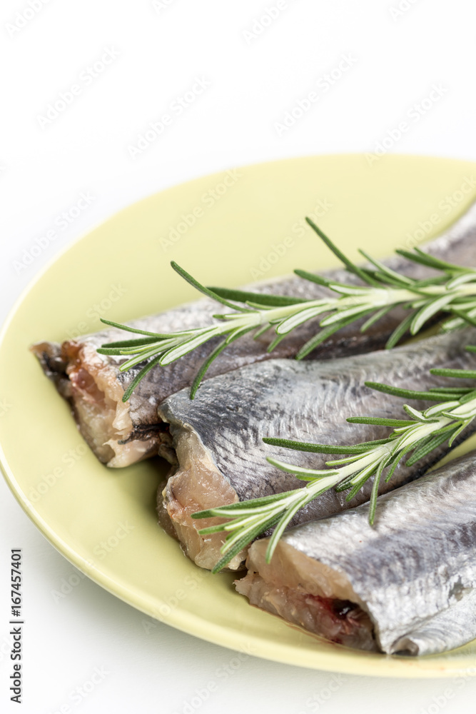 Slices of raw hake fish with rosemary branches on the plate Slices of raw hake fish with rosemary branches on the plate