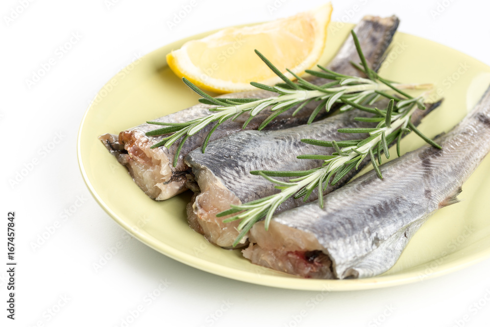 Fresh raw hake fish with rosemary and lemon on the plate