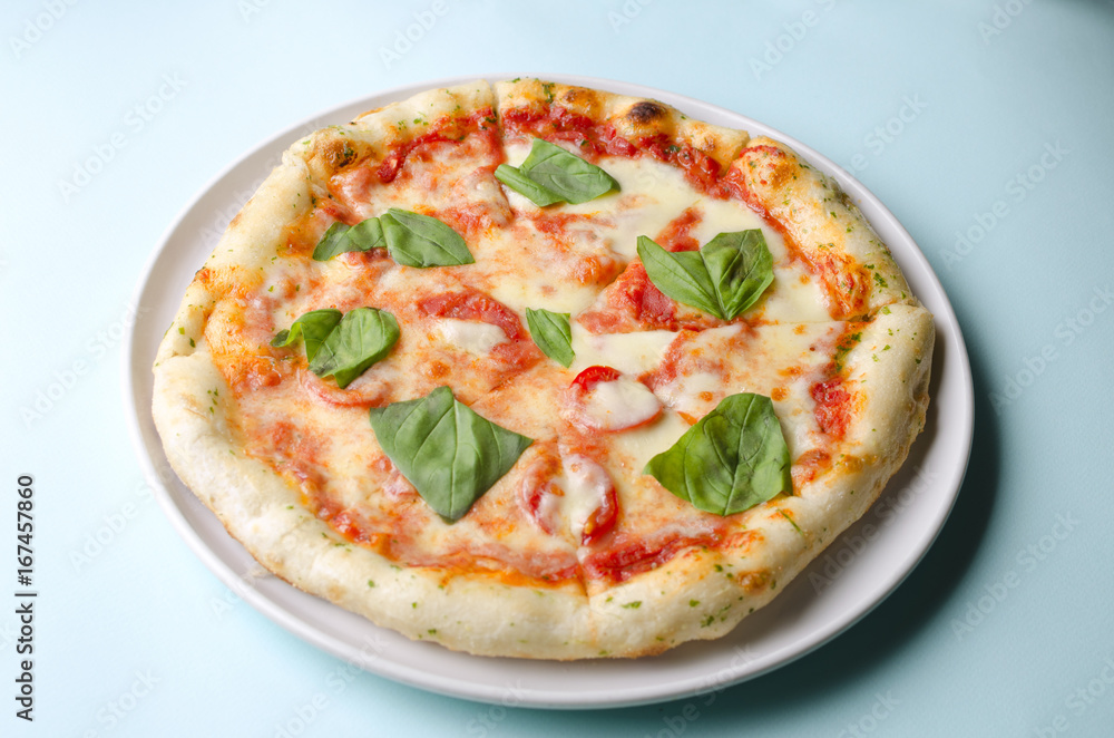 Pizza margarita on a white plate and blue background