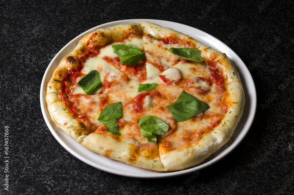 Pizza margarita on a white plate and blue background