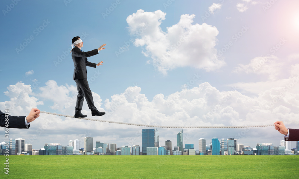 Business concept of risk support and assistance with man balancing on rope Business concept of risk support and assistance with man balancing on rope