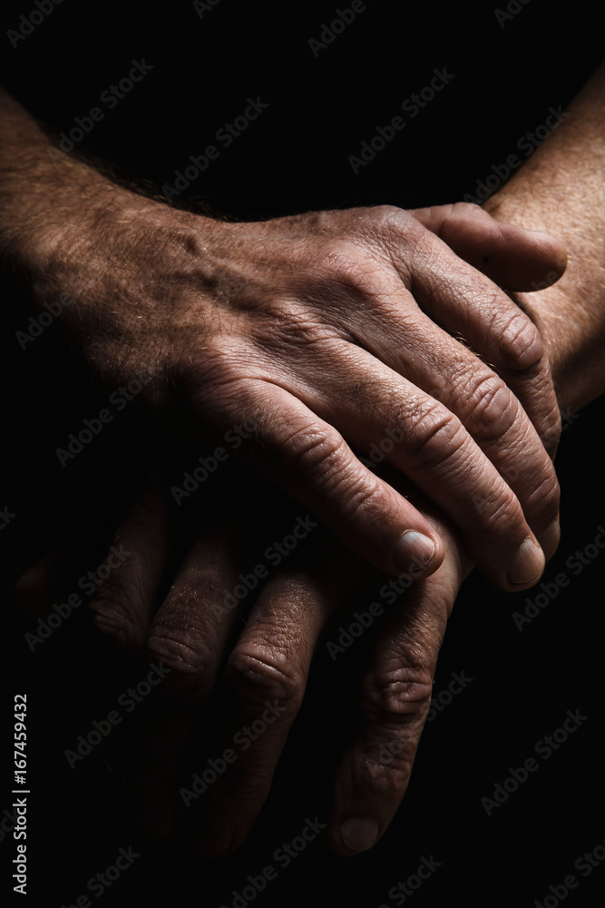 Fototapeta premium Hands of an elderly man's palms together, thought about problems, with dramatic lighting