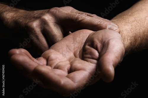 Hands of an elderly man with two fingers measuring the pulse. Lots of texture and character in the old man hands