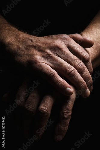 Hands of an elderly man's palms together, thought about problems, with dramatic lighting