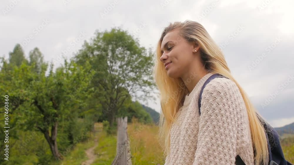 Beautiful girl posing at the camera and smiling on a background of forest and mountain village