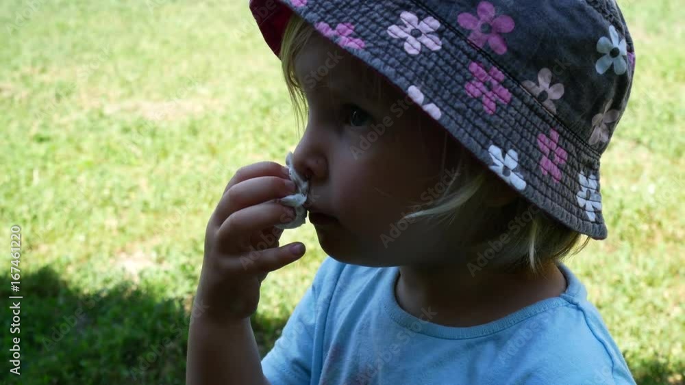 The little girl is wiping her nose with a napkin. The little girl is wiping her nose with a napkin.