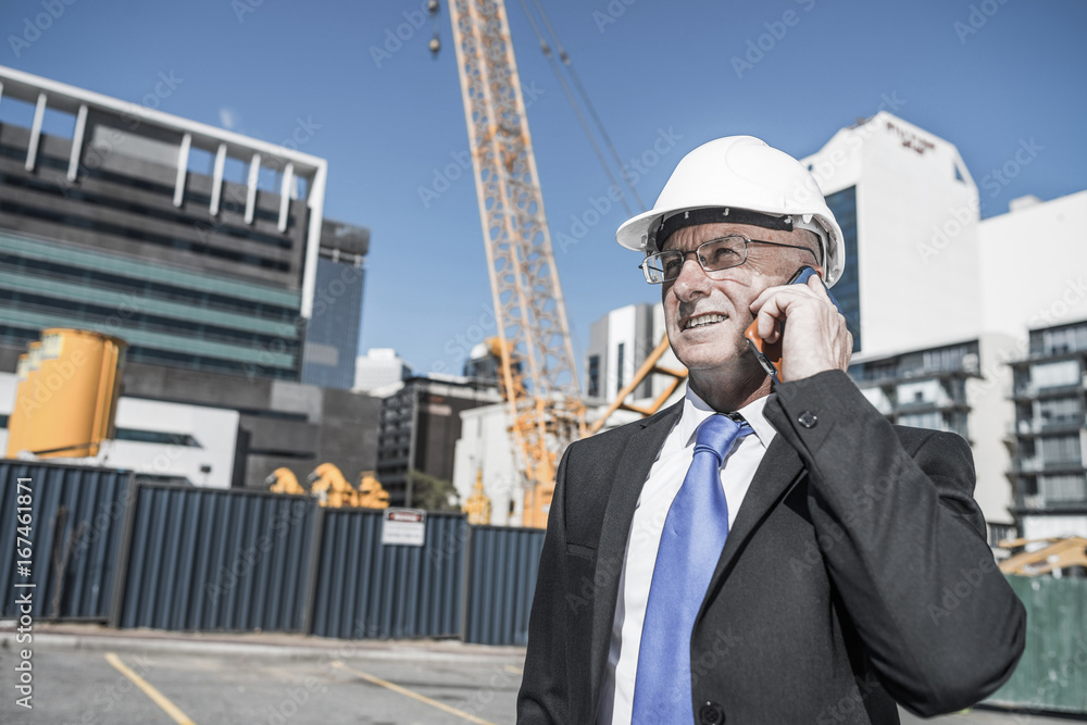 Man architector outdoor at construction area having mobile conve Man architector outdoor at construction area having mobile conve