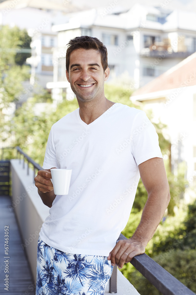Fototapeta premium Man enjoying morning coffee on balcony, portrait