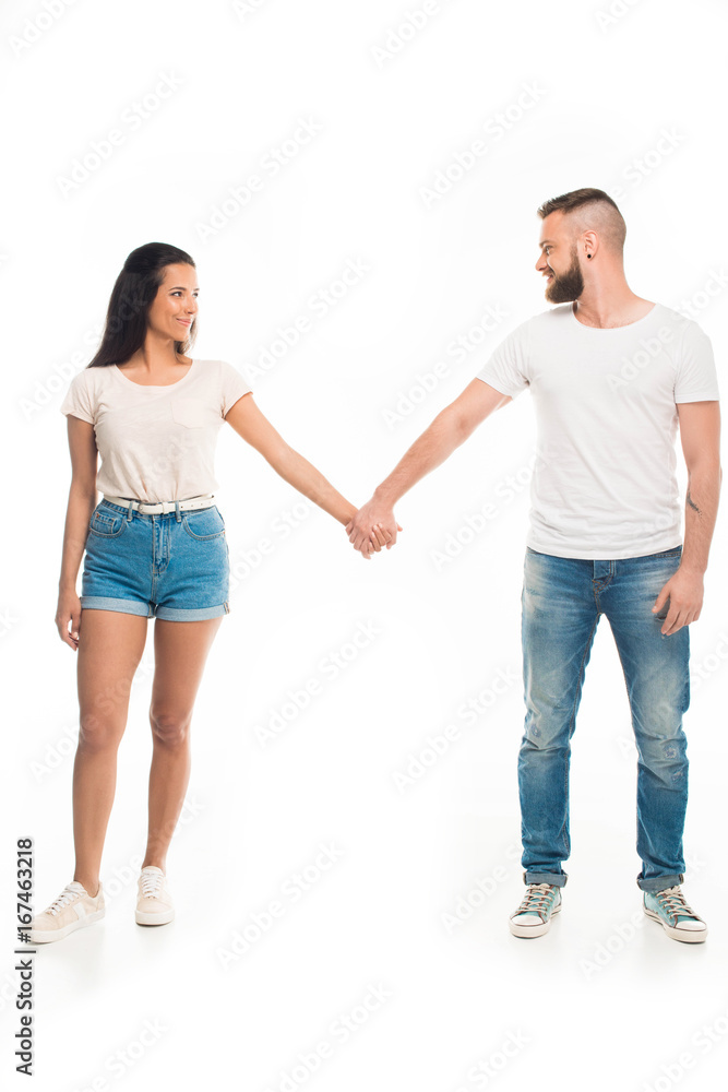'Full length portrait of young attractive couple holding hands, isolated on white