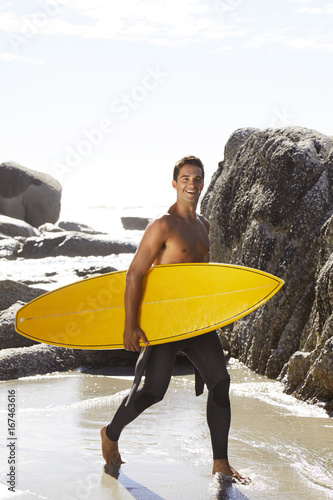 Smiling surfer dude holding surfboard on beach © sanneberg
