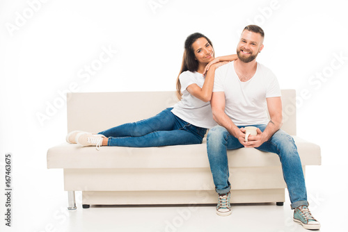 'portrait of young attractive couple sitting on couch, isolated on white