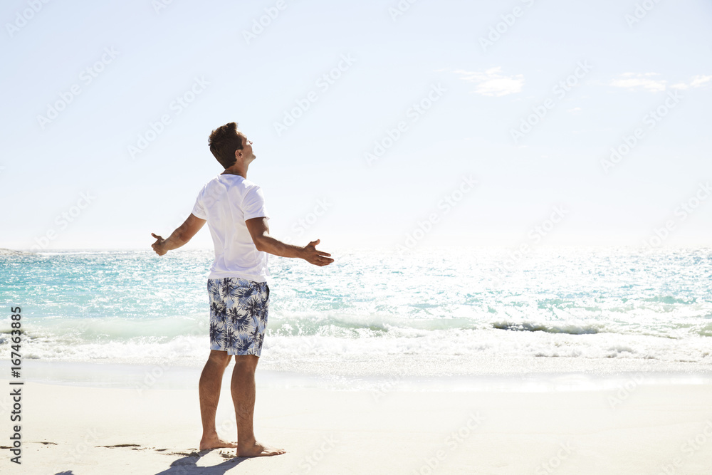 Dude on vacation standing on beach in sun
