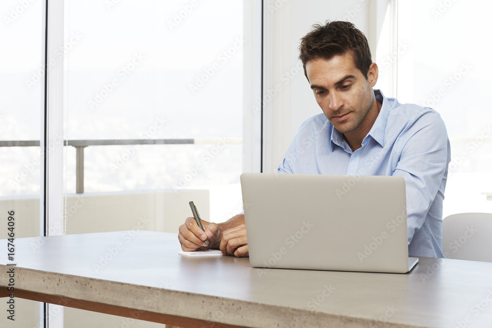 Dude working from home using laptop and notepad Dude working from home using laptop and notepad