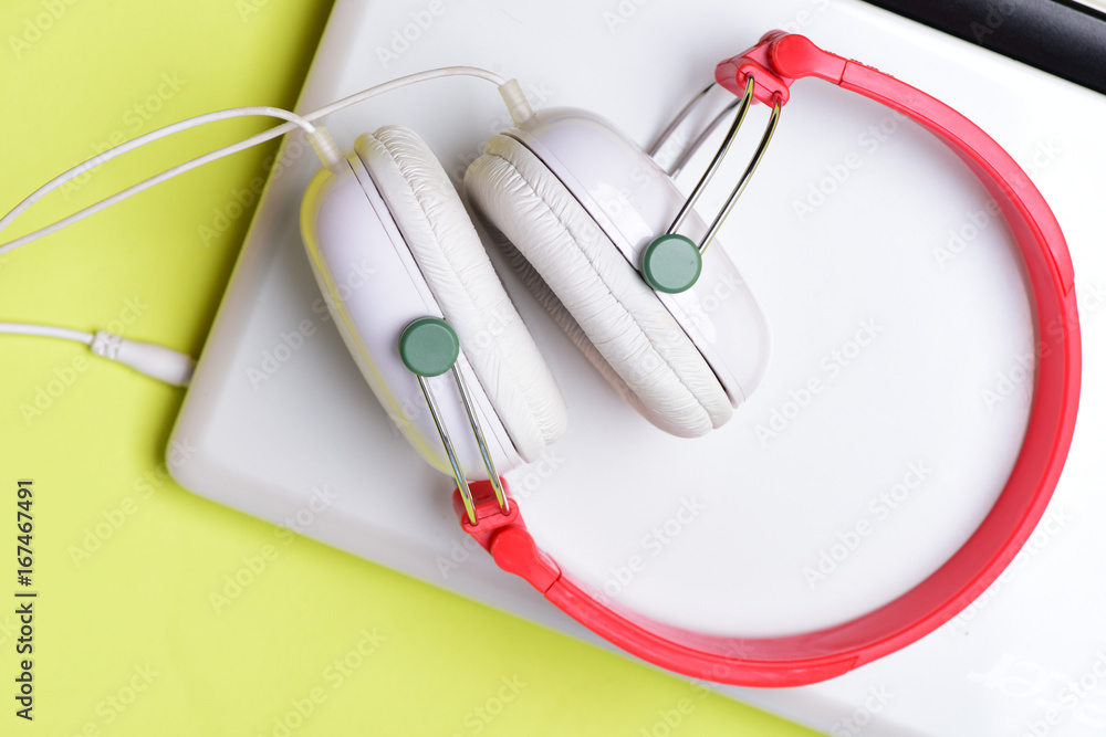 Earphones made of plastic with computer. Headphones and silver laptop
