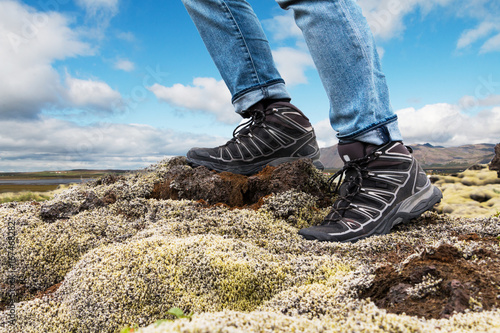 Concept of active lifestyle, investigating, exploring and travel. Man's feet in hiking shoes against nature background.