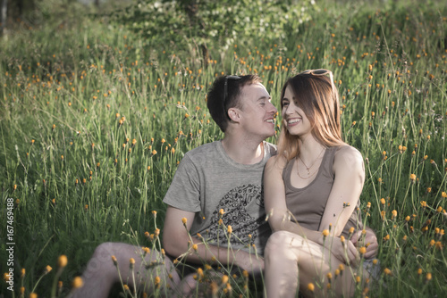 Happy loving couple in nature among yellow flowers photo