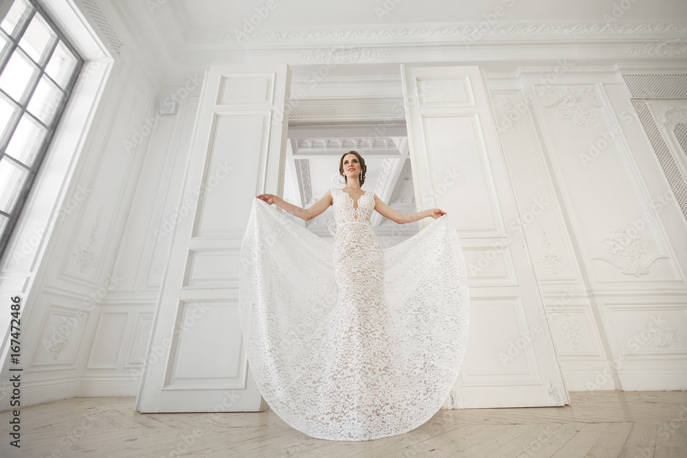 Beautiful bride posing in wedding dress in a white photo Studio. Mirror. Sofa. Bouquet. The door. Chandelier. Beautiful bride posing in wedding dress in a white photo Studio. Mirror. Sofa. Bouquet. The door. Chandelier.