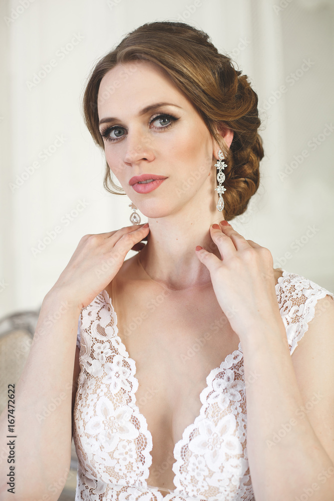 Beautiful bride posing in wedding dress in a white photo Studio. Mirror. Sofa. Bouquet. The door. Chandelier.