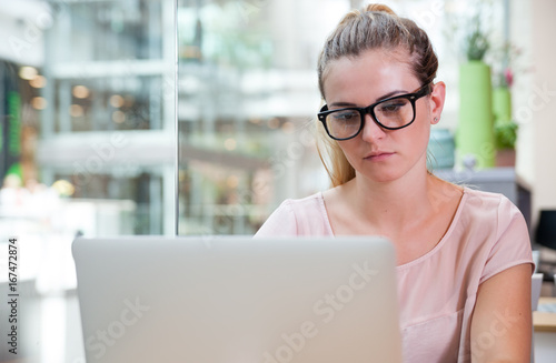 Business woman working with laptop at open space office in modern interior