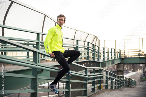 Male runner sitting on a hand rail photo