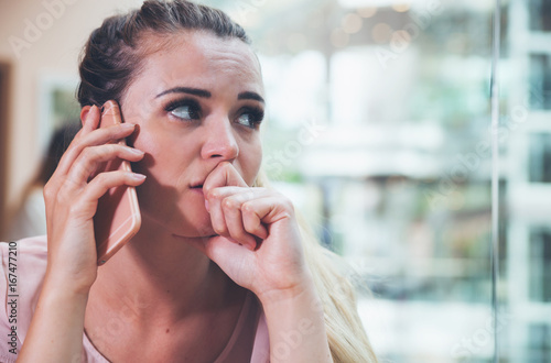 Stressed girl talking on phone at cafe