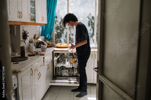 Young man empties the dishwasher. photo