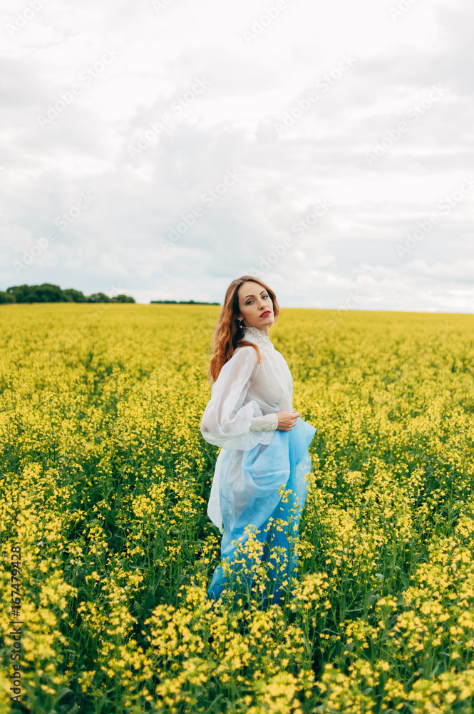 Beautiful girl in a dress among yellow flowers in a field Beautiful girl in a dress among yellow flowers in a field