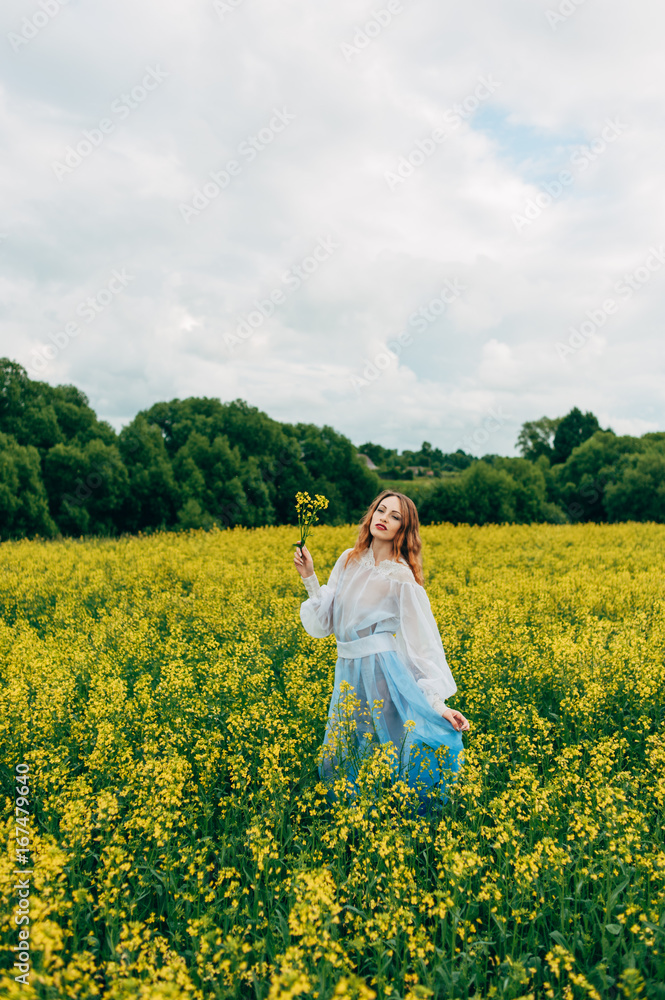 Beautiful girl in a dress among yellow flowers in a field Beautiful girl in a dress among yellow flowers in a field