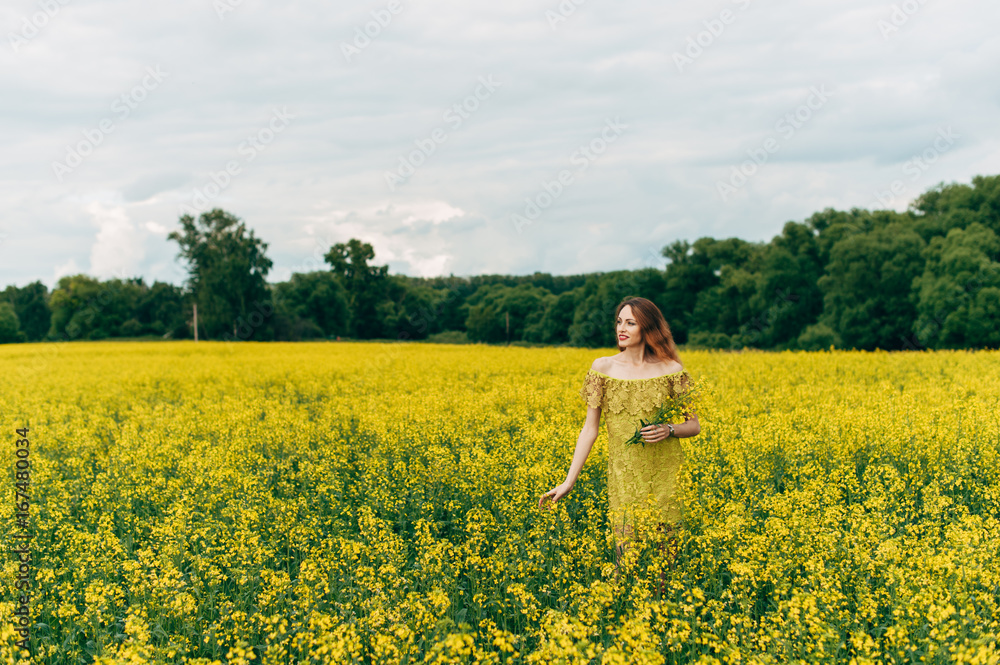 Beautiful girl in a dress among yellow flowers in a field Beautiful girl in a dress among yellow flowers in a field
