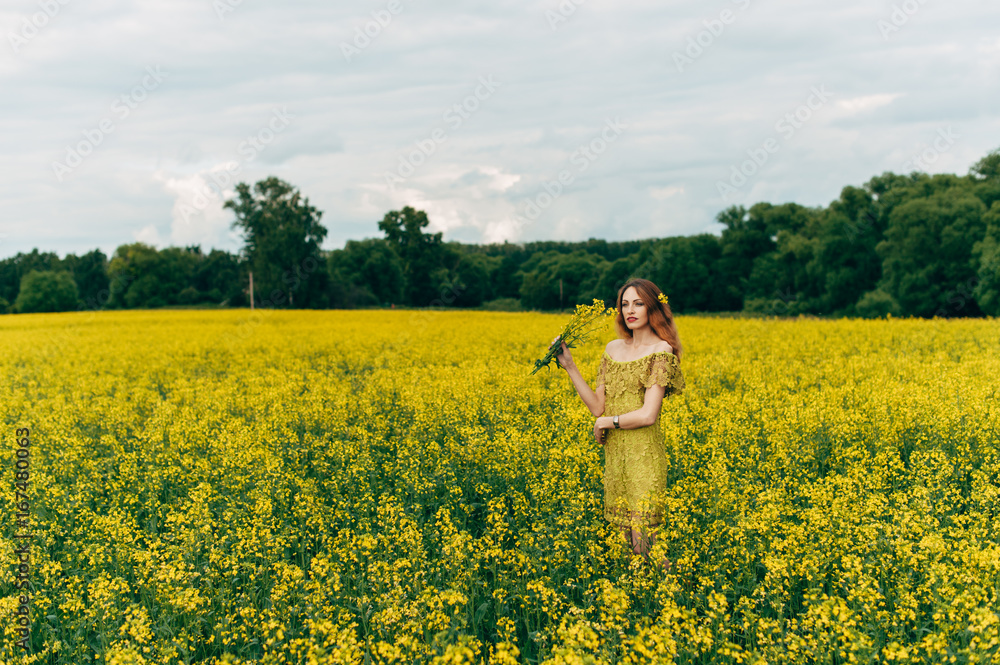 Beautiful girl in a dress among yellow flowers in a field Beautiful girl in a dress among yellow flowers in a field