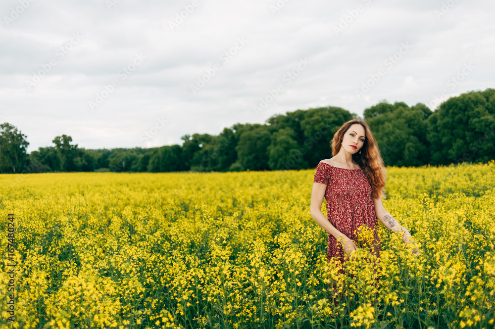 Beautiful girl in a dress among yellow flowers in a field Beautiful girl in a dress among yellow flowers in a field