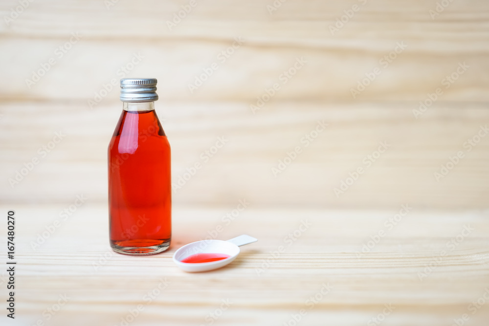 Red syrup of medicine with tea spoon on wood background. Red syrup of medicine with tea spoon on wood background.