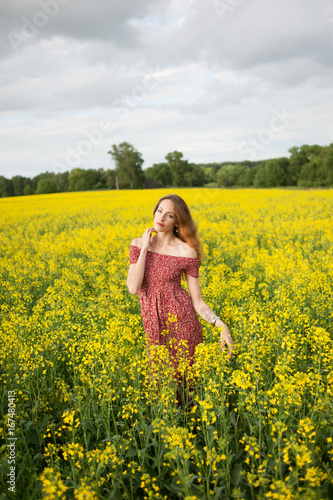 Beautiful girl in a dress among yellow flowers in a field