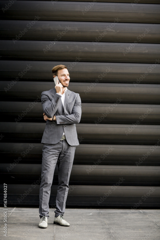 Handsome businessman with mobile phone by office building Handsome businessman with mobile phone by office building