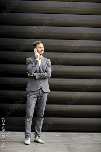 Handsome businessman with mobile phone by office building © BGStock72