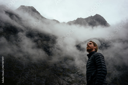 Man in his down jacket looking towards the cold foggy sky as the weather changes