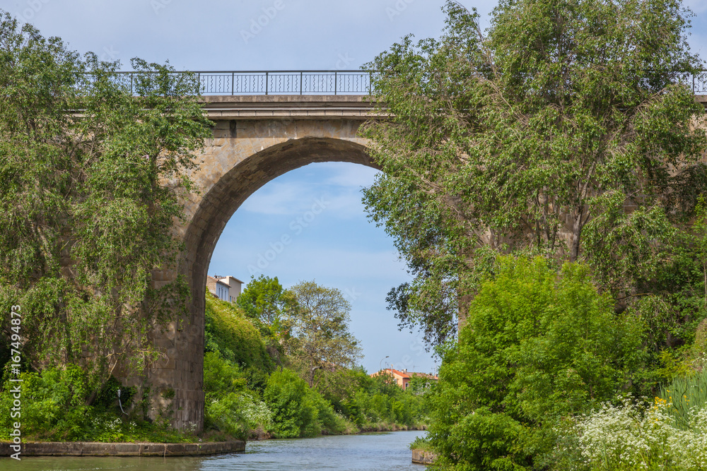 a bridge above canal du Midi with green trees and water
