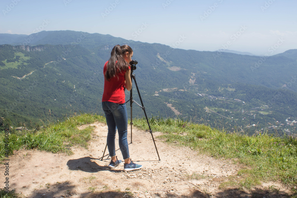 Traveller looking the nature from the high mountain with spotting scope, binoculars tripod