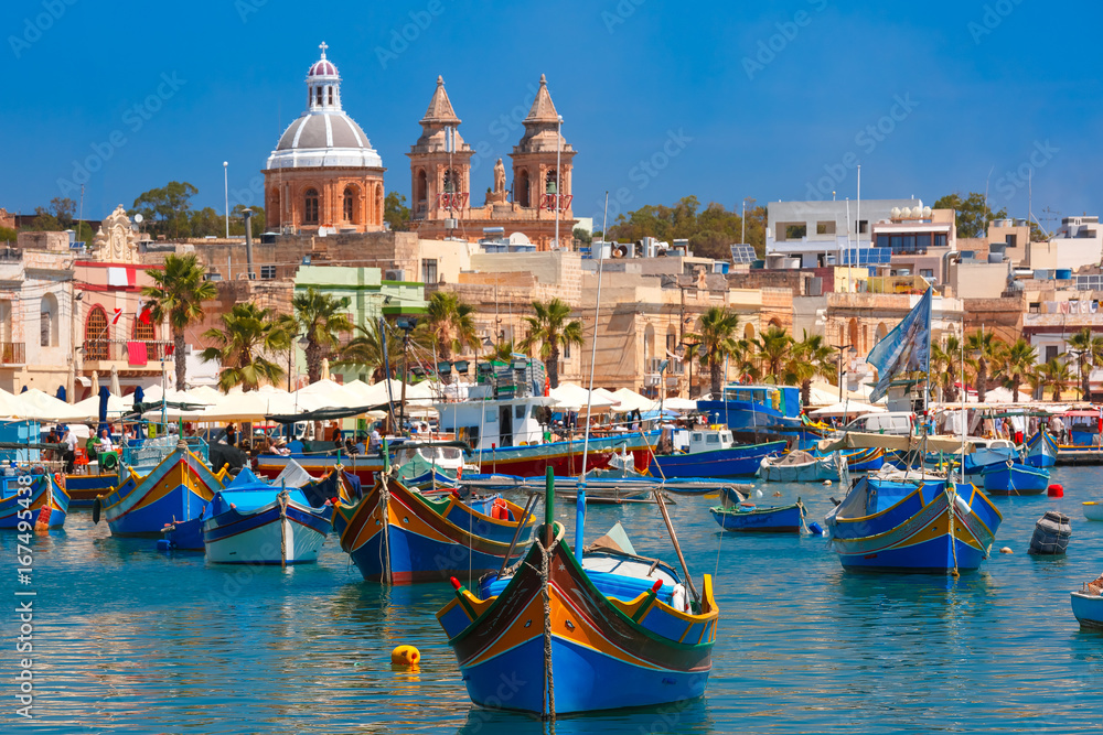 Fototapeta premium Tradycyjne eyed kolorowe łodzie Luzzu w porcie śródziemnomorskiej wioski rybackiej Marsaxlokk, Malta