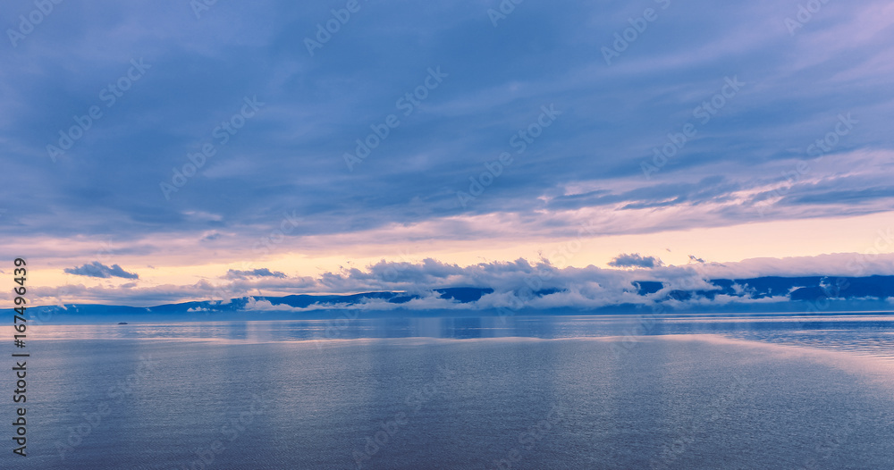 Fototapeta premium Sunset in the calmness on the lake and slowly floating boat
