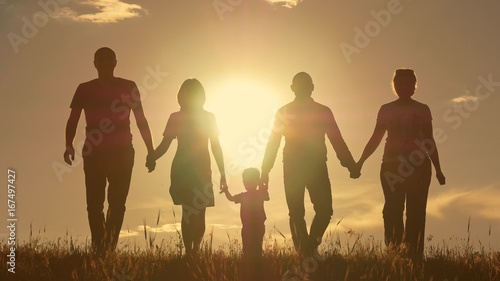 Happy young family with children running around the field, silhouette at sunset