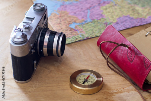 Traveler's things: old camera, map, notebook, compass on a wooden background